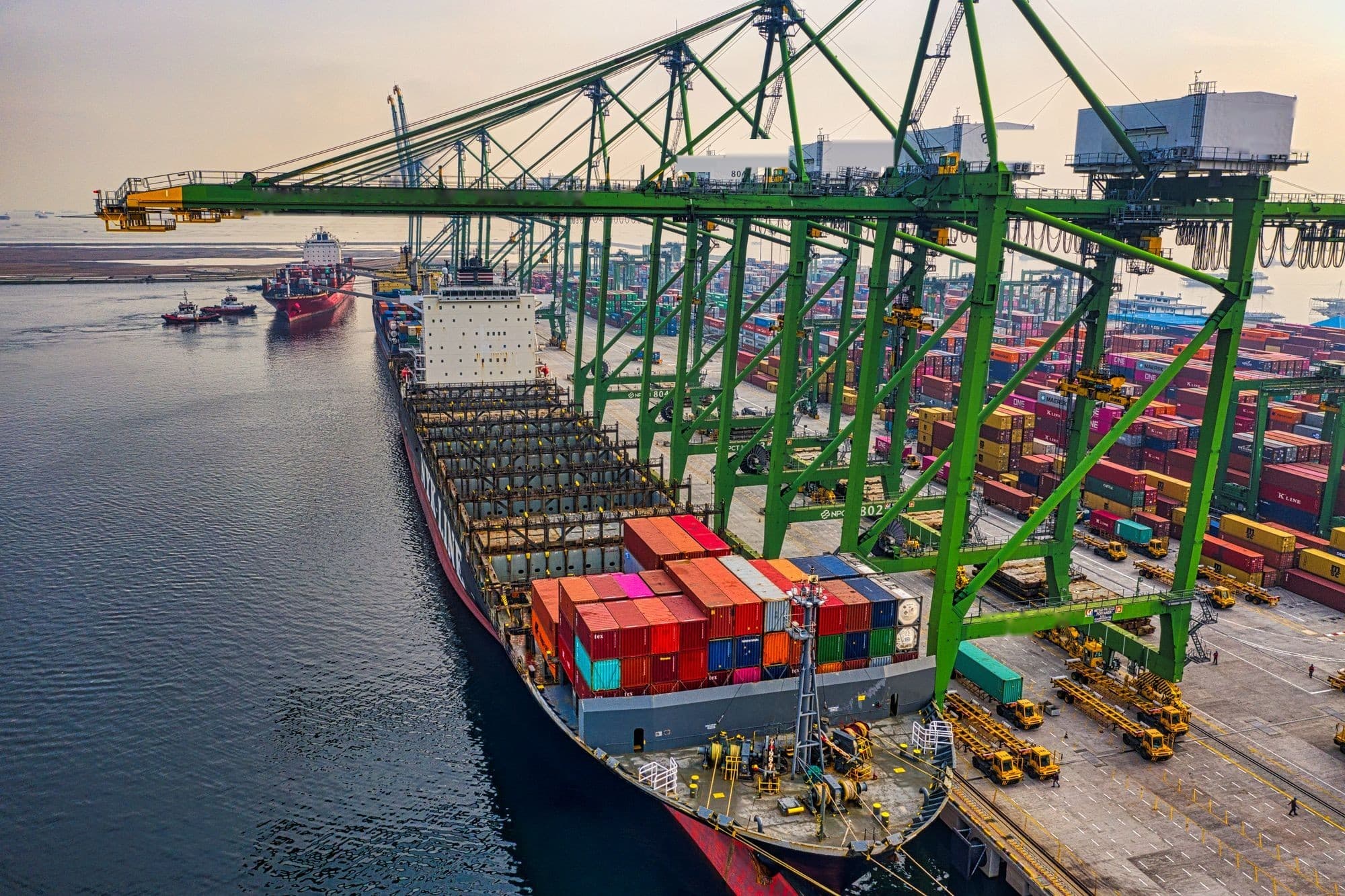 Navio porta-contêineres atracado no terminal do Porto de Paranaguá ao fim da tarde, com guindastes de pórtico